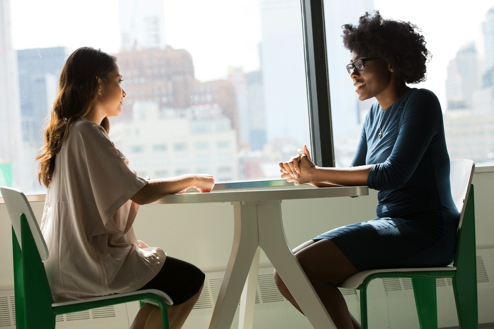 Twee vrouwen zitten aan tafel en voeren een zelfverzekerd gesprek